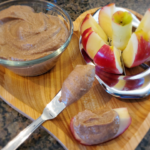 Homemade Nutella fruit dip with apples on a wooden tray, Healthy chocolate hazelnut spread next to sliced apples, YMCA nutritious homemade Nutella with dates and hazelnuts