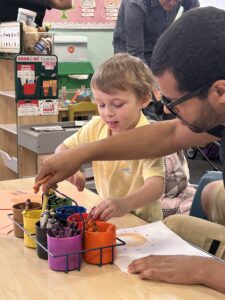 YMCA teacher and preschooler coloring a picture together in a cheerful classroom as part of affordable early learning in Berks County.