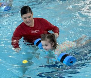 A YMCA swim instructor teaching a child to swim at the Reading YMCA